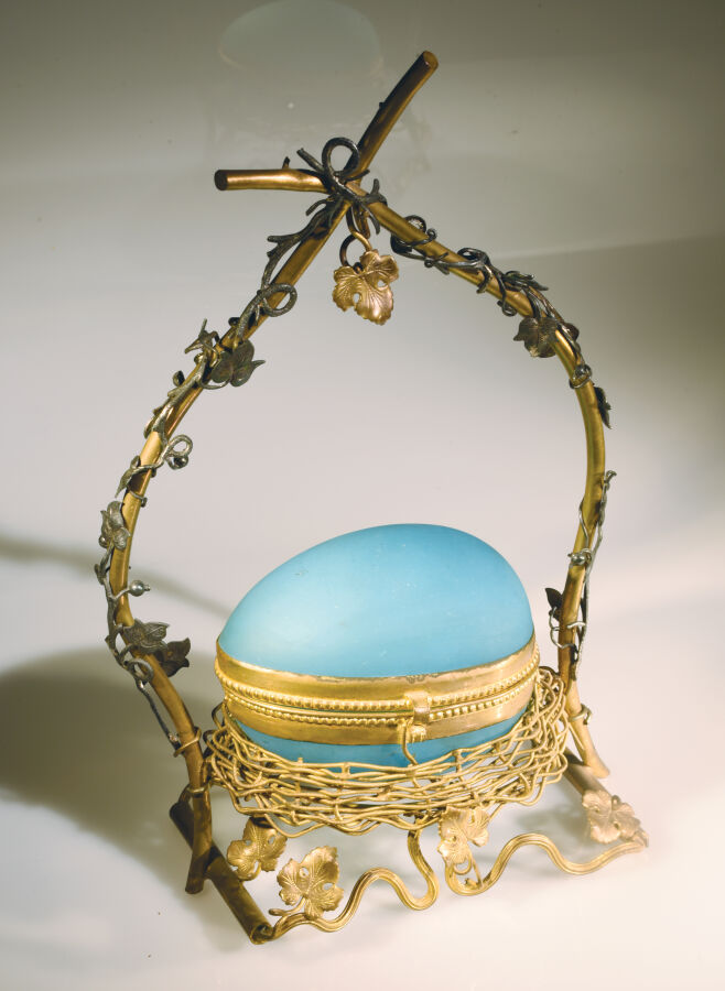Boîte en forme d'oeuf en opaline satinée bleue présentée dans un nid en pomponn…