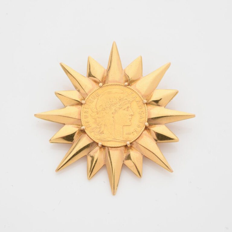 Broche Soleil en or jaune (750) ornée d'une pièce de 10 francs or 1906 dans un…