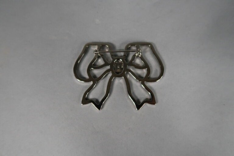 CHANEL - Broche noeud en métal argenté ajouré soulignée de strass - Avec boîte…