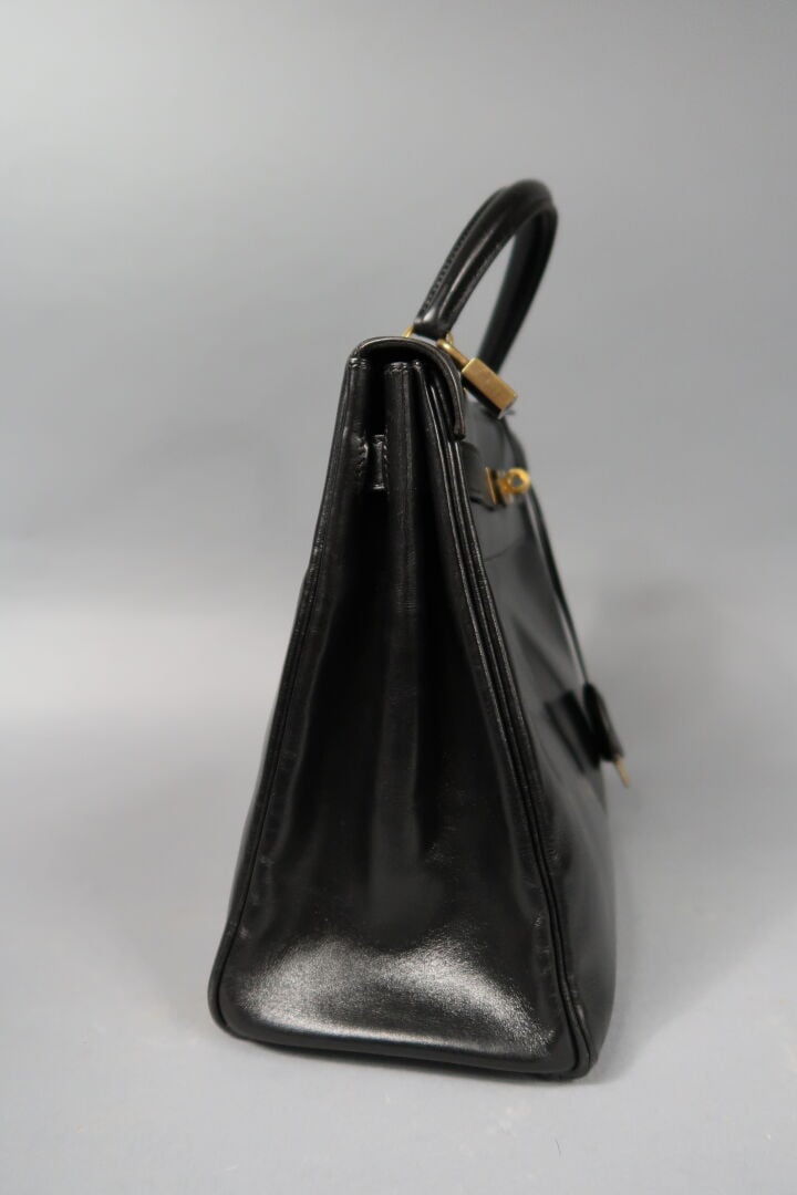 HERMES - Sac «Kelly retourné» 32cm en box noir, attributs dorés, clefs, clochet…