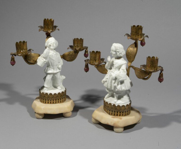 Paire de candélabres à décor d'un couple en porcelaine blanche présentant trois…