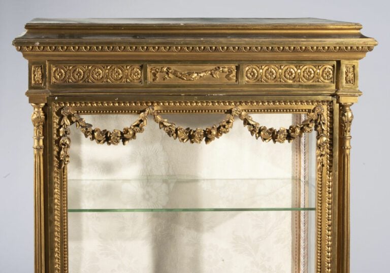 Vitrine en bois doré à colonnes détachées ornée de guirlandes de fleurs, rosace…