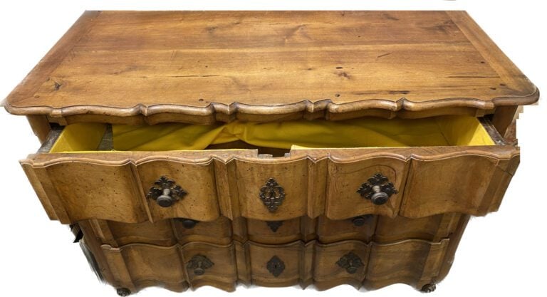 Commode en noyer à façade arbalète ouvrant à trois tiroirs, pieds à enroulement…