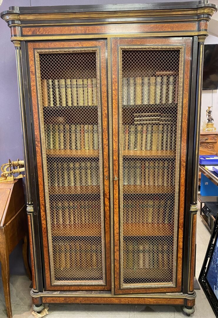Bibliothèque en bois noirci et placage de loupe de thuya, ouvrant à deux portes…