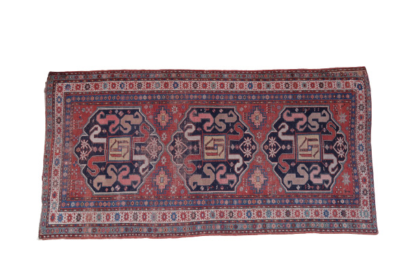 CAUCASE - Tapis en laine à décor de motifs stylisés et frises sur fond rouge -…