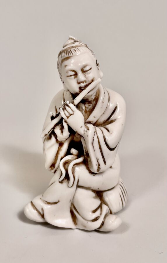 Statuette en porcelaine blanche représentant un joueur de flute assis. - Gravur…