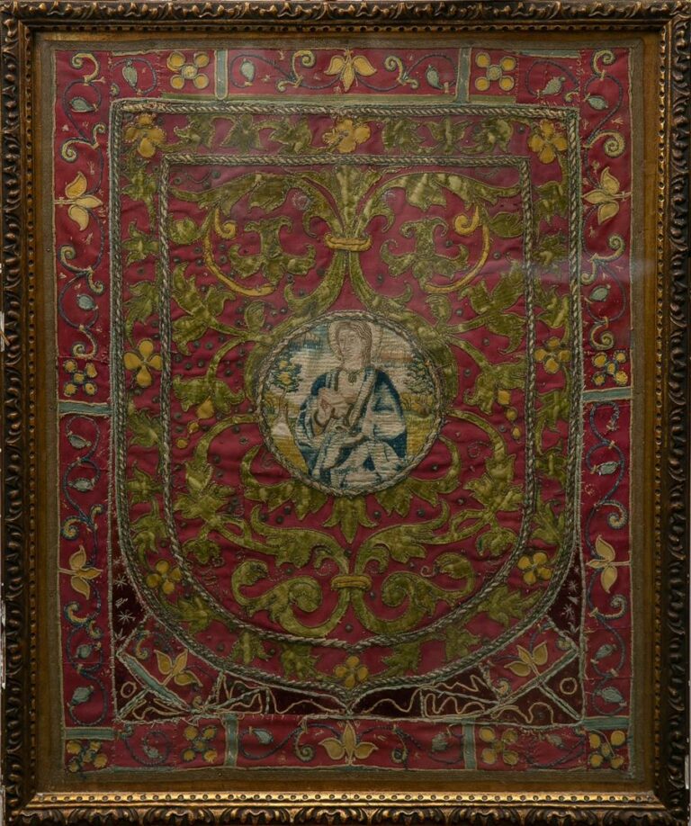 Broderie encadrée sur fond rouge, à décor d'un saint-personnage dans un médaill…