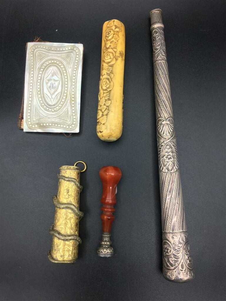 Trois manches d'ombrelle, le plus grand en métal argenté à décor repoussé, le s…