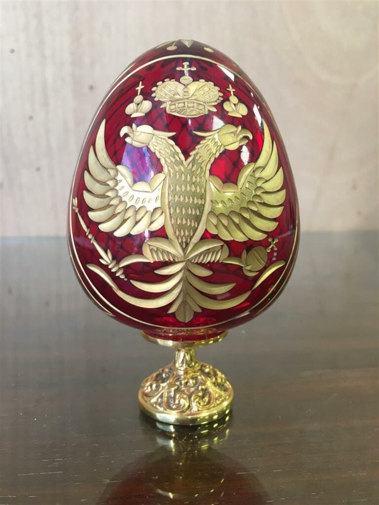 FABERGE. - Oeuf en cristal taillé rouge, sur son socle en métal doré signé et n…