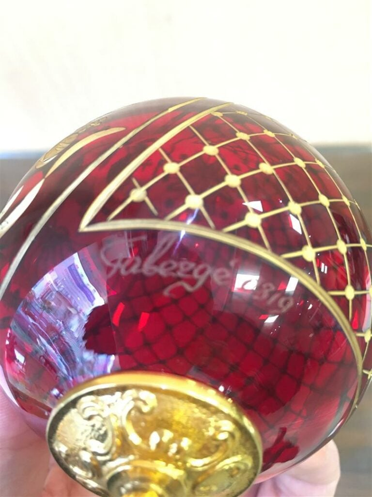 FABERGE. - Oeuf en cristal taillé rouge, sur son socle en métal doré signé et n…