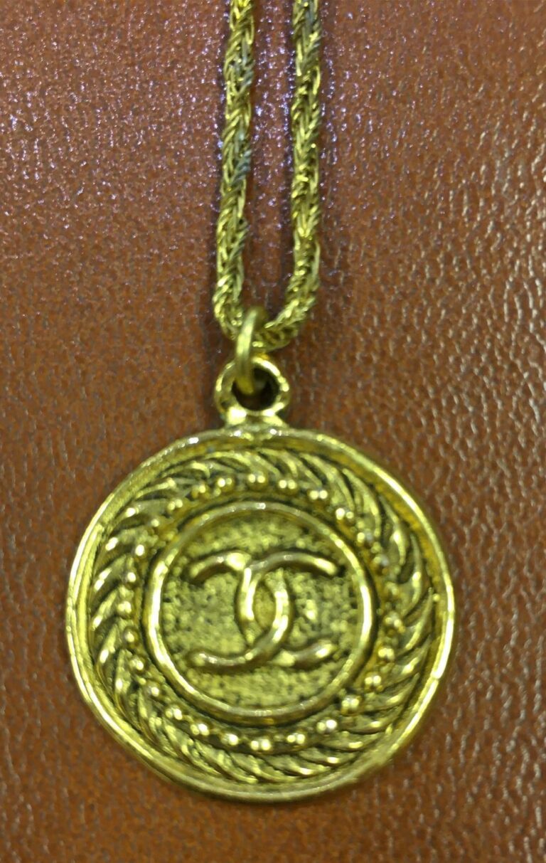 CHANEL. - Collier chaîne retenant un pendentif en métal doré circulaire, signé,…
