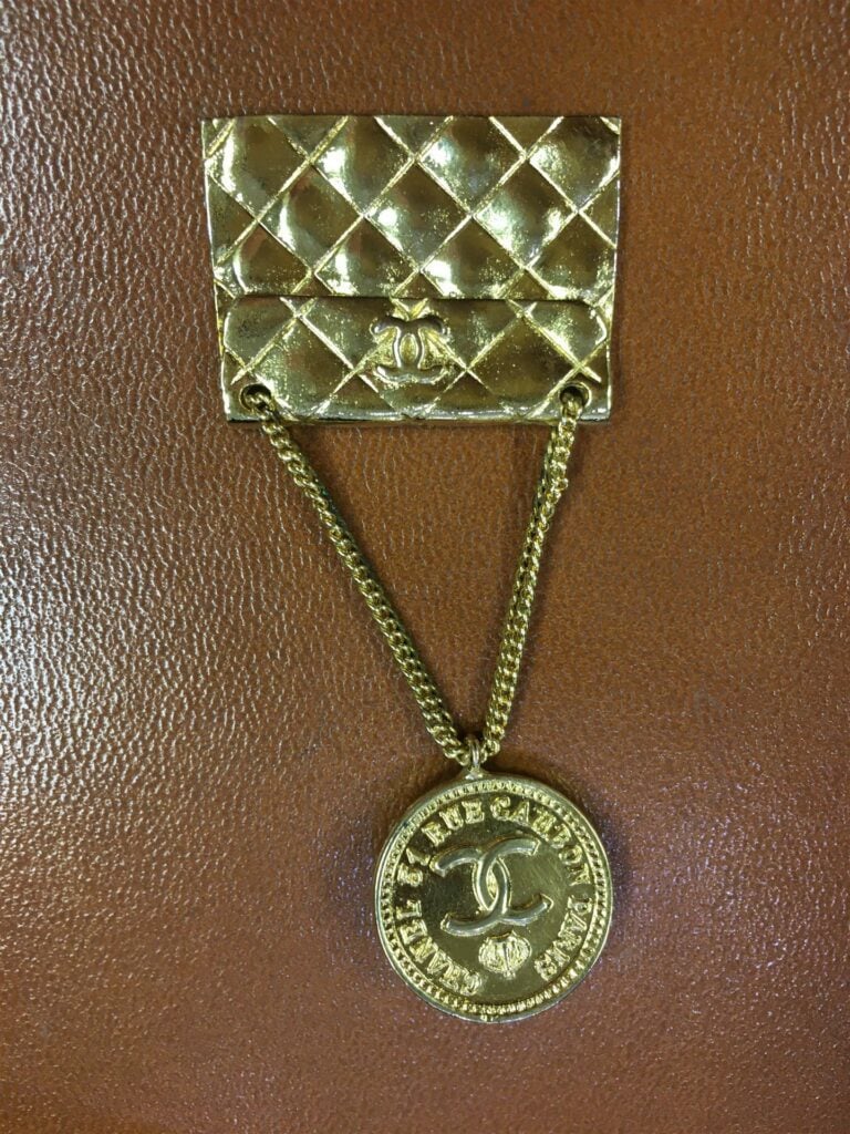 CHANEL. - Broche en métal doré représentant un sac classique, signée sur plaque…