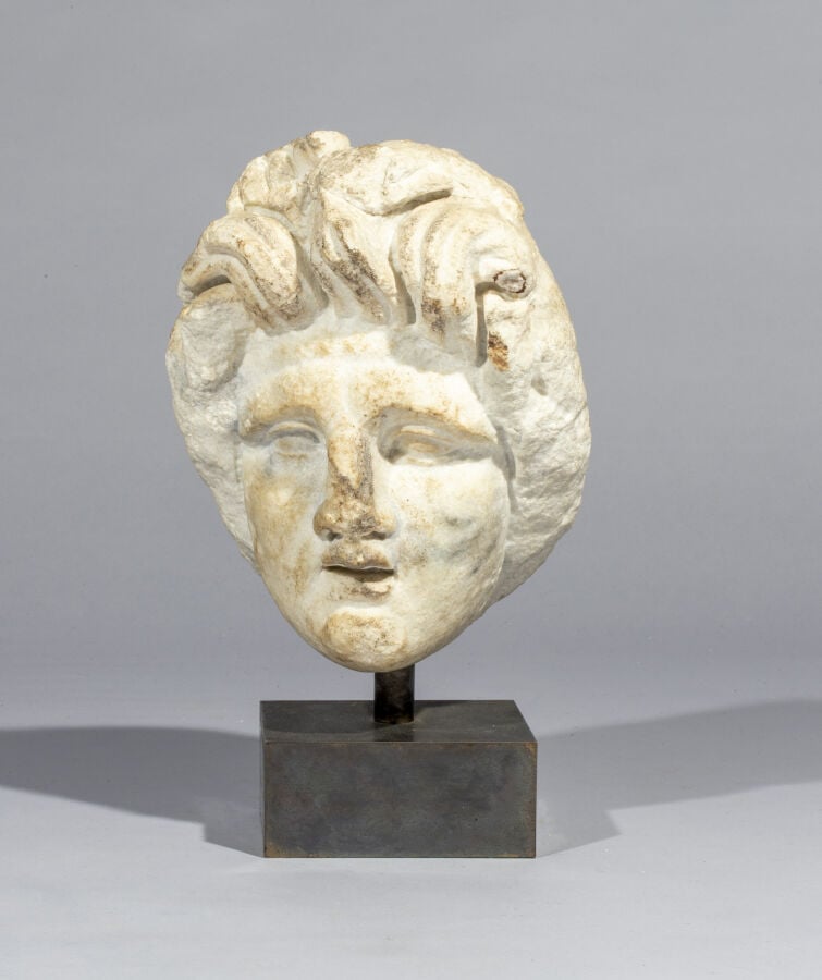 Tête de femme à la coiffure composée de longues mèches ébouriffées. Il s'agit d…