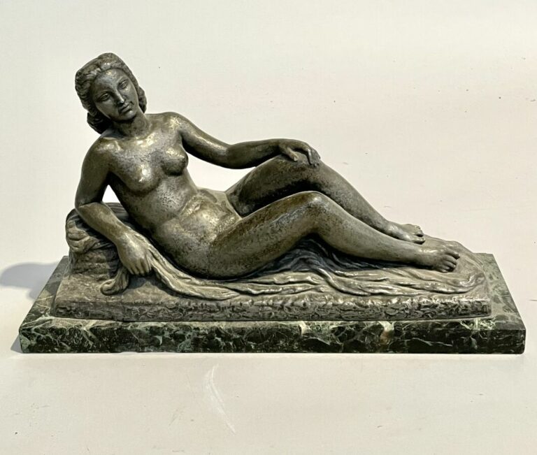 Sculpture en régule représentant une femme nue allongée sur un drapé. Socle en…