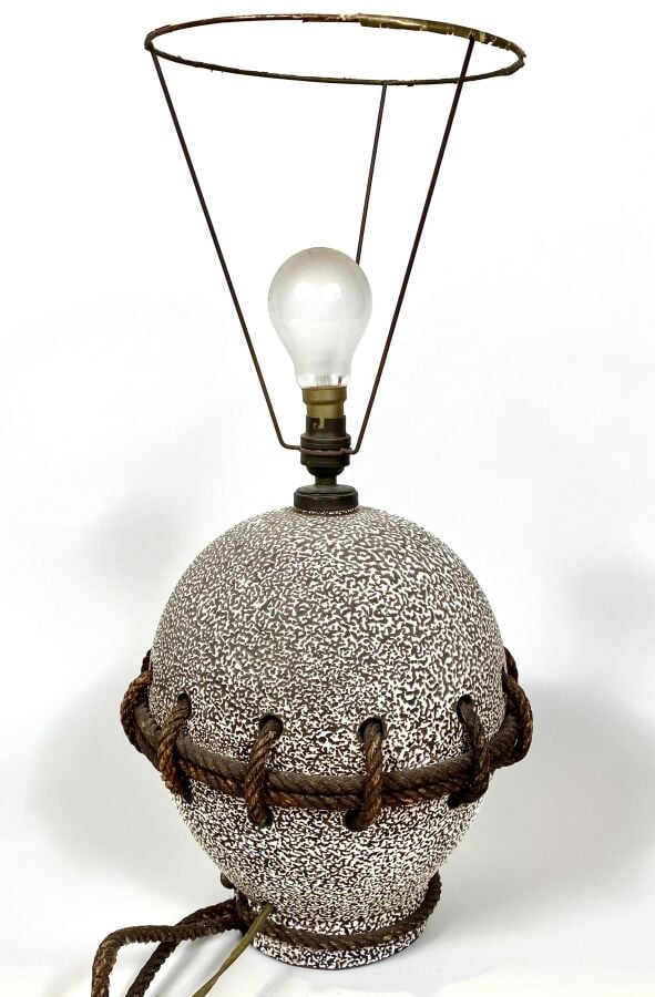 LAMPE OVOIDE en céramique à émail granuleux sur fond beige. Elle présente des o…