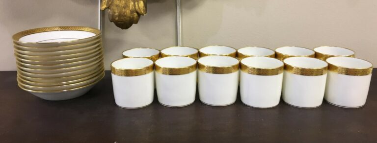 Douze tasses à café en porcelaine de Limoges blanche et filets dorés.