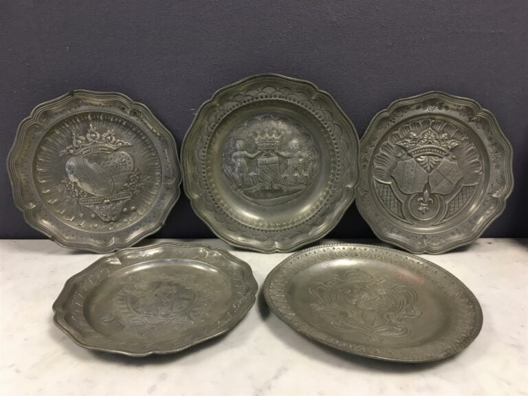 Cinq assiettes en étain à décor repoussé.