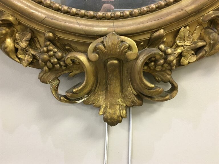 Miroir de forme ovale en bois sculpté, ajouré et doré à décor de fleurs et pamp…
