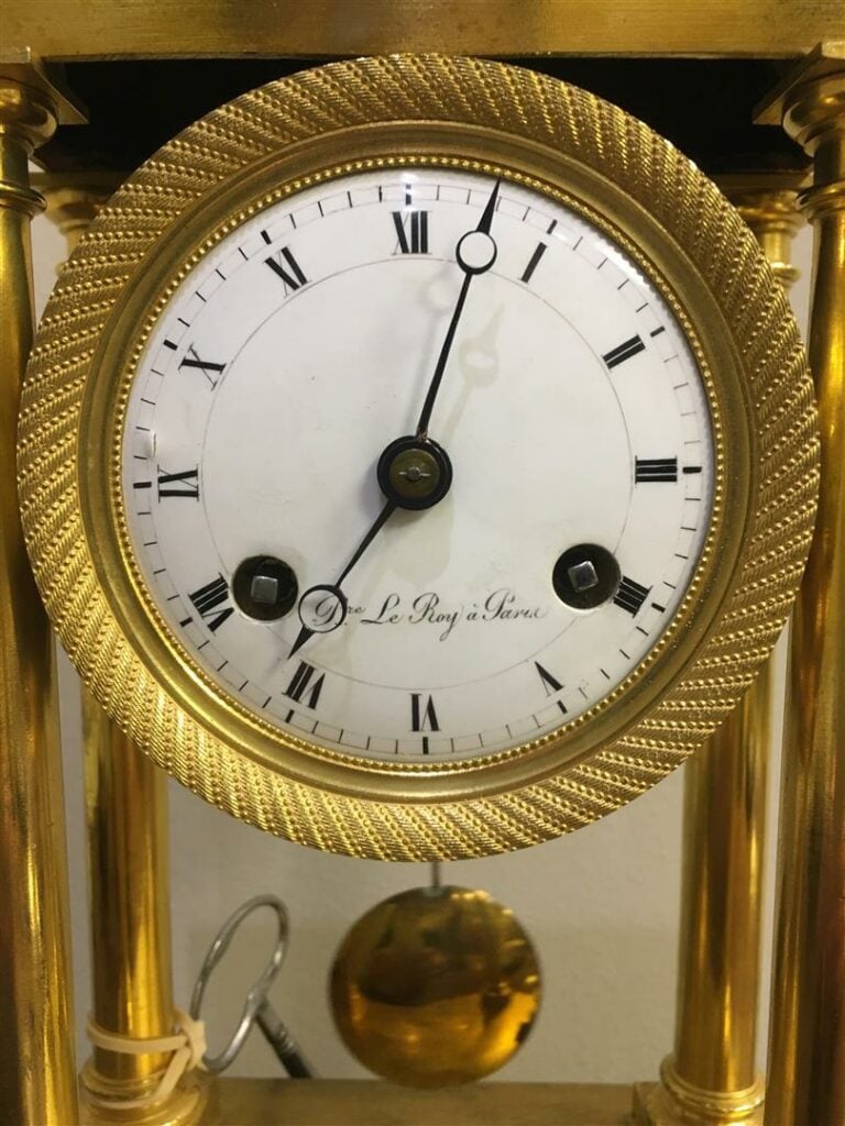 Pendule portique en bronze doré, les montants en colonnes doriques, le cadran é…