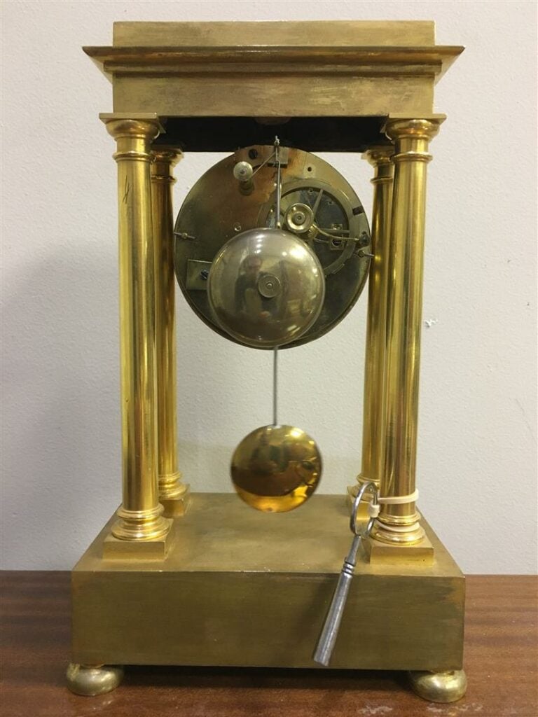 Pendule portique en bronze doré, les montants en colonnes doriques, le cadran é…