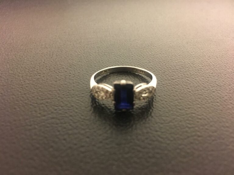 Bague en platine serti d'un saphir de taille émeraude, cerné de deux boucles aj…