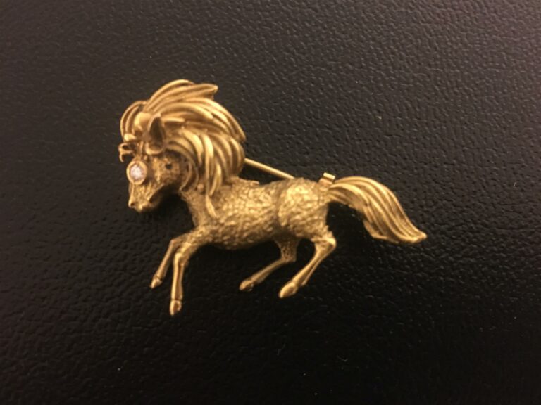 Broche or jaune 750/1000 représentant un cheval au galop, la crinière stylisée.…