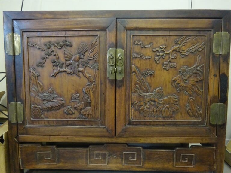 Buffet bas en bois patiné, ouvrant à deux portes sculptées de chiens de fô dans…