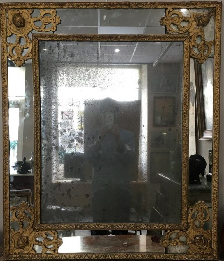 Miroir à encadrement en bois sculpté et doré, le fronton cintré à fond de glace…