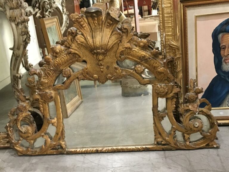 Miroir à encadrement en bois sculpté et doré, le fronton cintré à fond de glace…