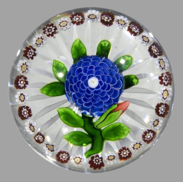 Baccarat. Presse-papiers orné d'une camomille bleue sur une tige verte portant…
