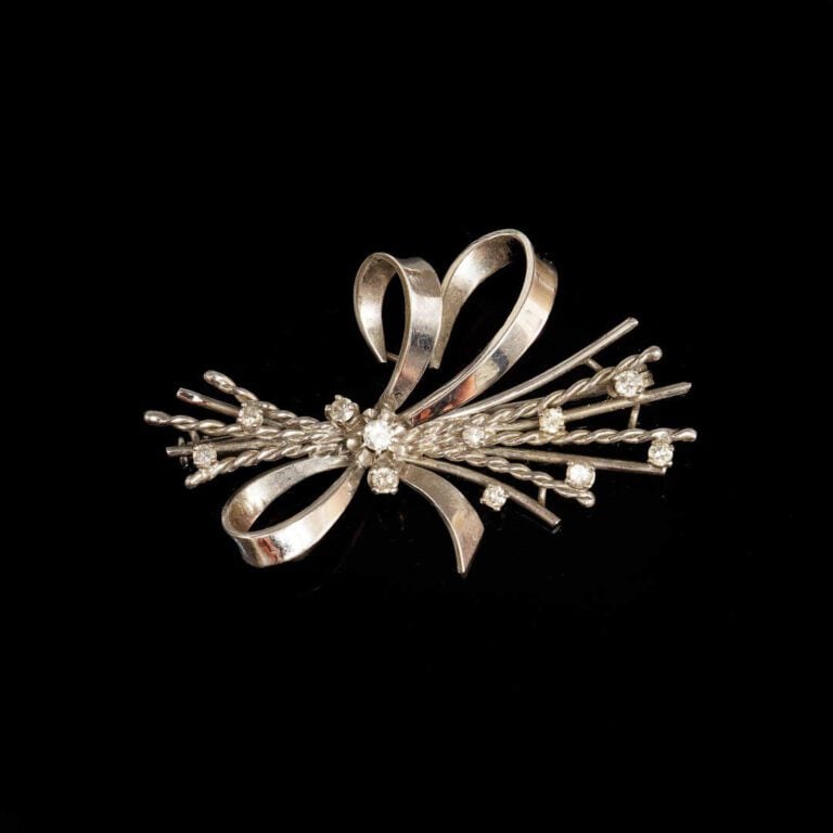 Broche en or blanc 18K (750°/oo) et platine (950°/oo) formant un noeud serti de…
