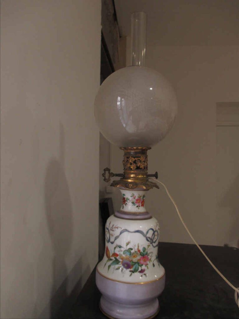 Lampe à pétrole en porcelaine à décor floral polychrome, globe en verre à décor…