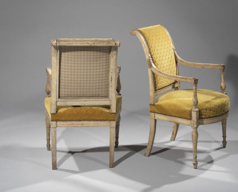 Paire de fauteuils en bois laqué crème à dossier éversé ; supports d'accotoirs…