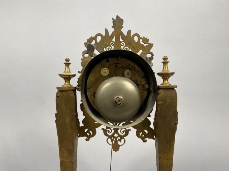 Pendule portique en bronze doré et ciselé. Les montants en forme de cariatydes…