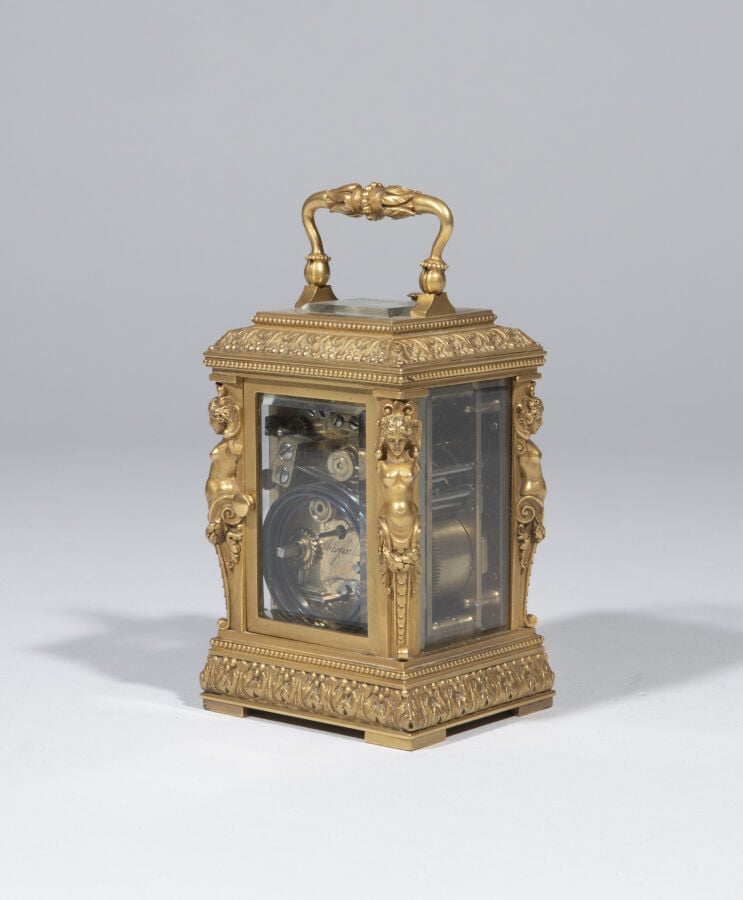 Pendulette en bronze doré , anse mobile ; elle présente aux quatre angles des t…