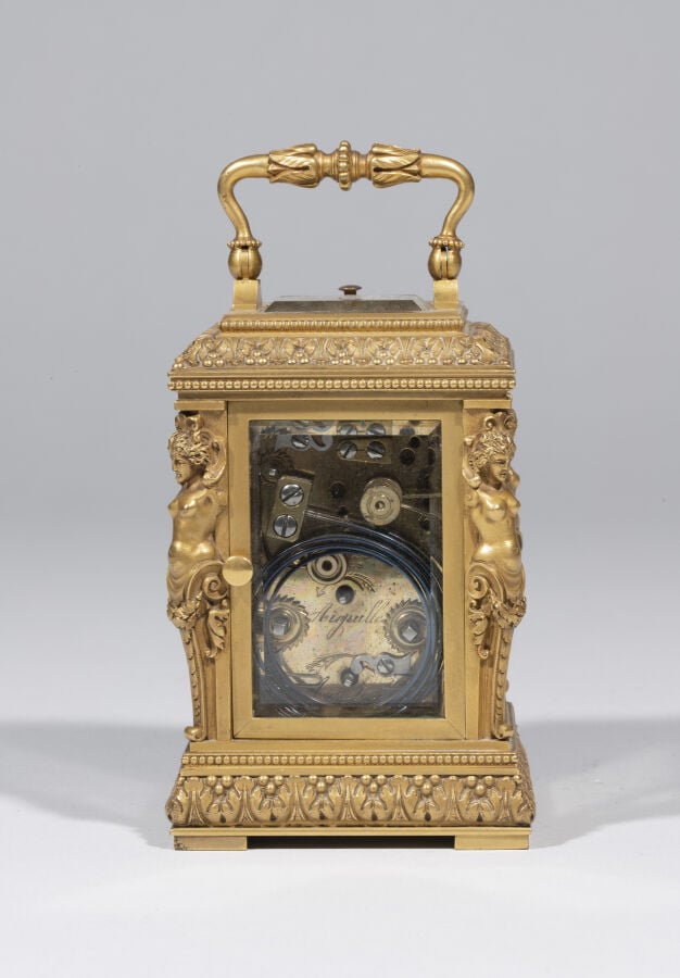 Pendulette en bronze doré , anse mobile ; elle présente aux quatre angles des t…