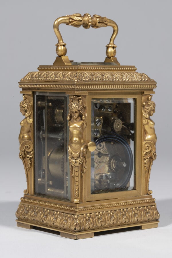 Pendulette en bronze doré , anse mobile ; elle présente aux quatre angles des t…