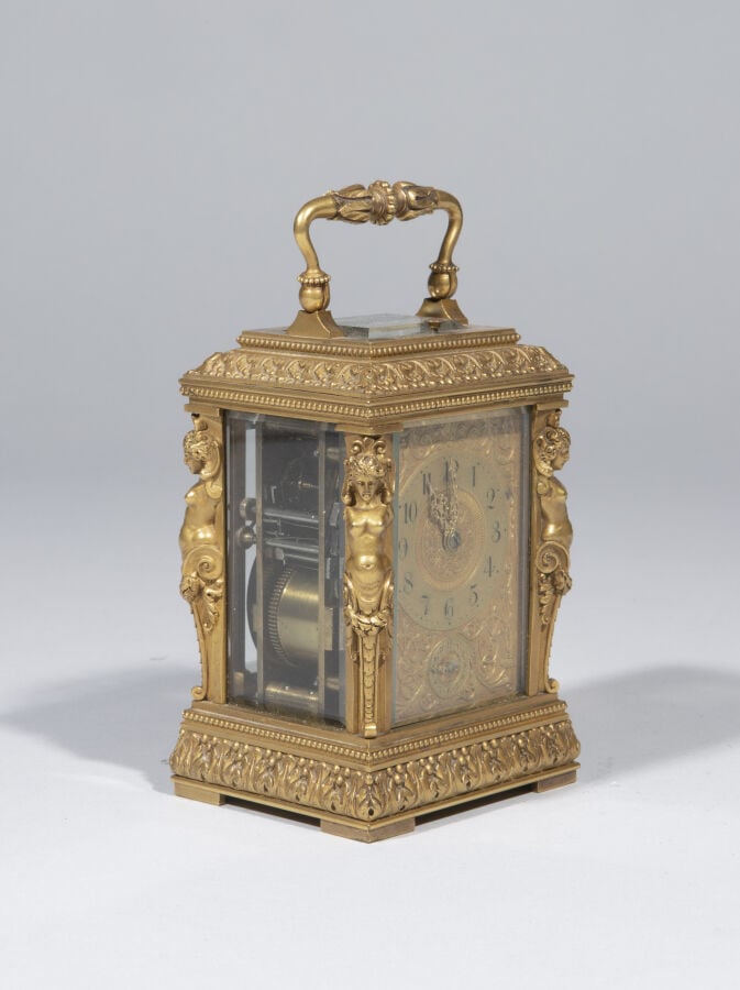 Pendulette en bronze doré , anse mobile ; elle présente aux quatre angles des t…