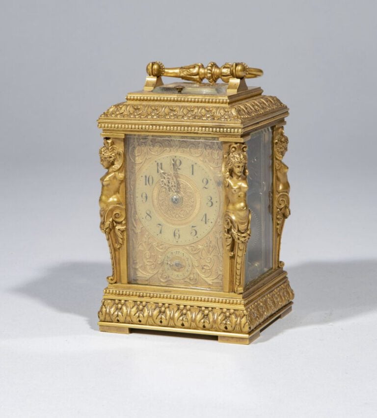 Pendulette en bronze doré , anse mobile ; elle présente aux quatre angles des t…