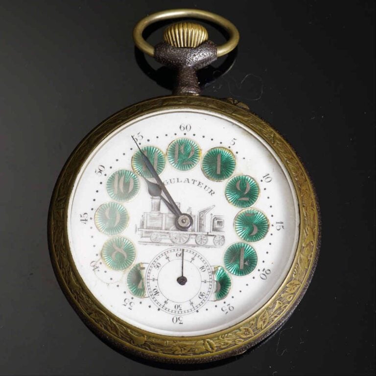 Régulateur en métal blanc de 6.5 cm. Cadran émaillé blanc orné d'une locomotive…