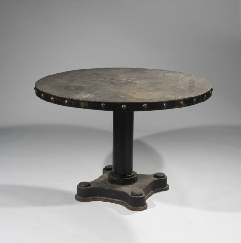 TABLE CIRCULAIRE en fonte laquée noire . La ceinture à ombilics simulant des cl…