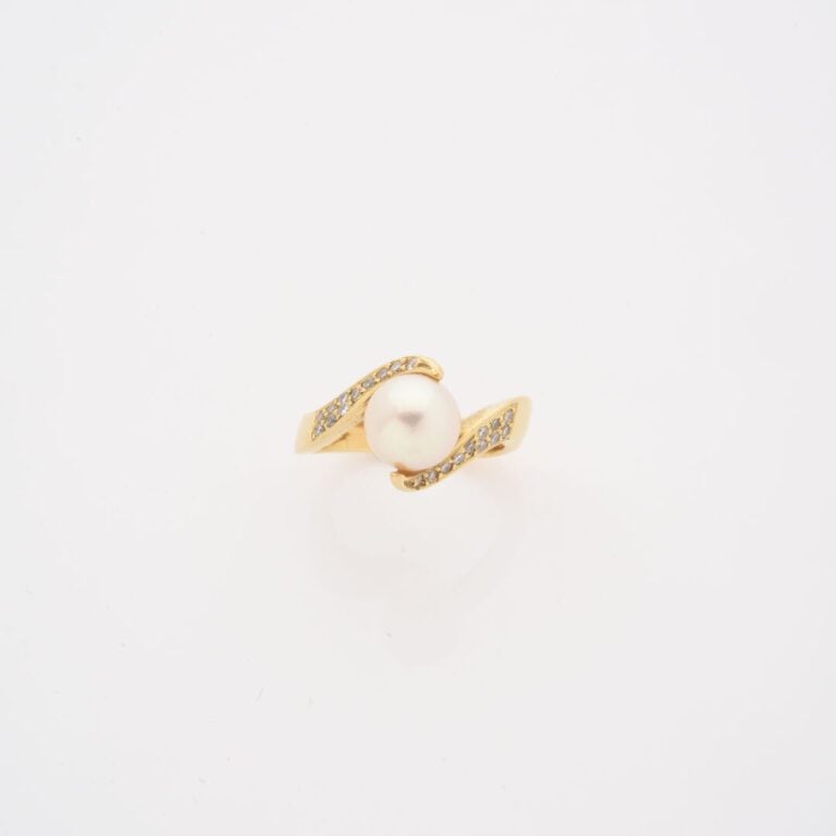 Bague en or jaune (750) ornée d'une perle de culture blanche épaulée de deux li…