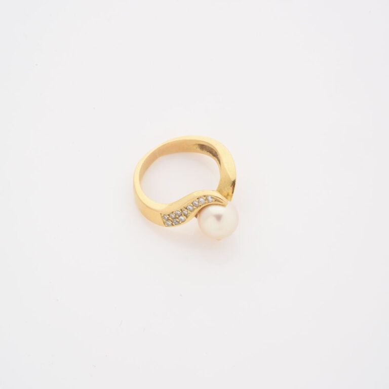 Bague en or jaune (750) ornée d'une perle de culture blanche épaulée de deux li…