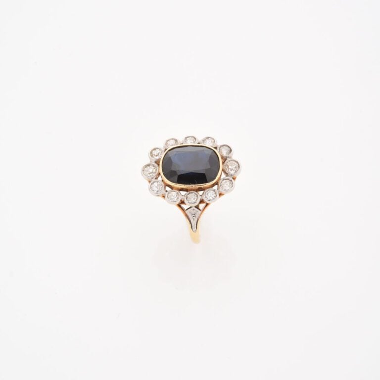 Bague marguerite en or jaune (750) ornée d'un saphir ovale facetté dans un ento…