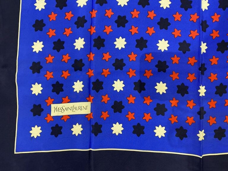 Yves SAINT LAURENT - Carré en soie à motif de semis étoilé sur fond bleu, bordu…