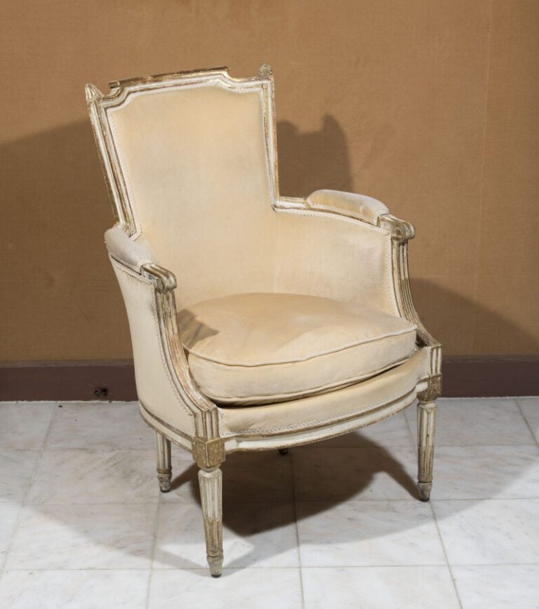 Bergère à dossier renversé en bois relaqué beige. Accotoirs à colonnettes. . Ep…