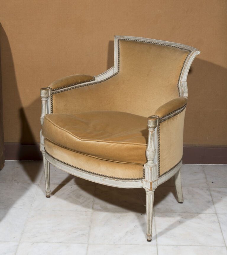 Bergère à dossier renversé en bois relaqué beige. Accotoirs à colonnettes. . Ep…