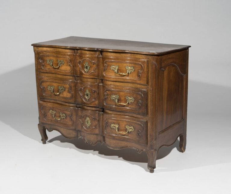 Commode en bois naturel mouluré et sculpté de forme rectangulaire. Elle présent…