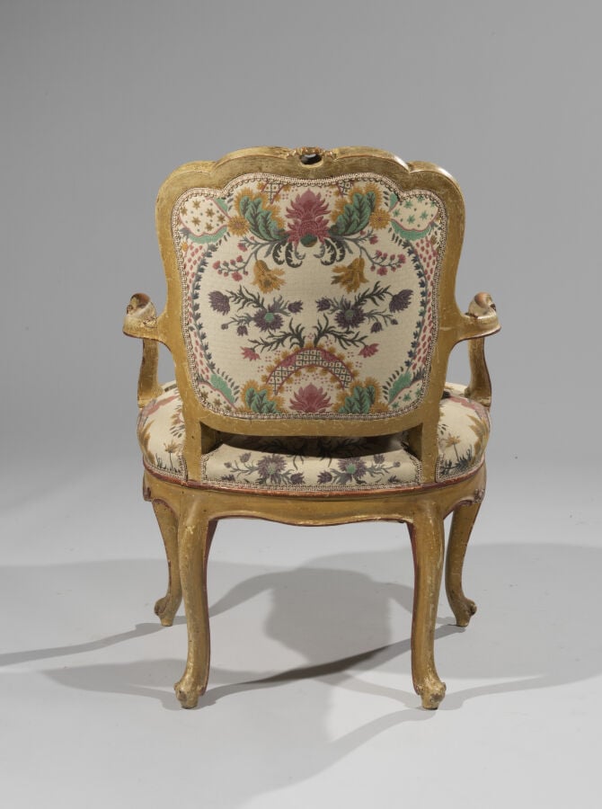 Fauteuil en bois mouluré, sculpté, laqué crème et peint à décor de fleurons ; l…