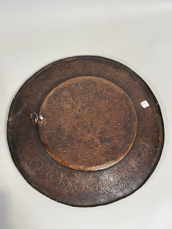 Plat rond en cuivre à décor au repoussé de fleurettes dans des réserves. Diamèt…